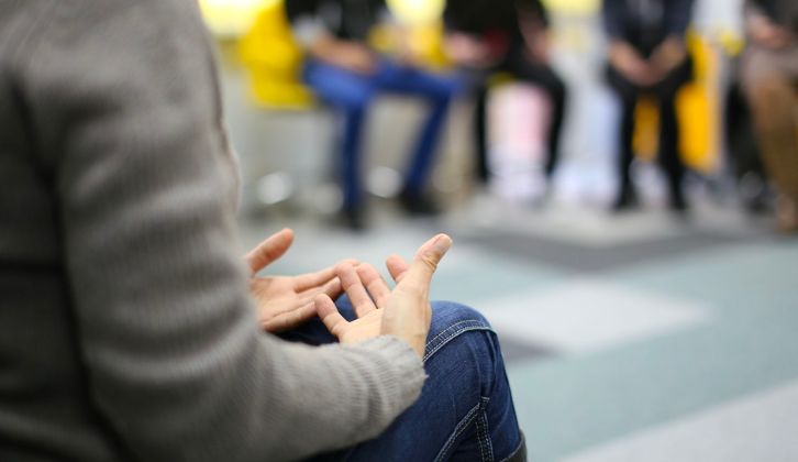 A person sits in a circle while gesturing with their hands
